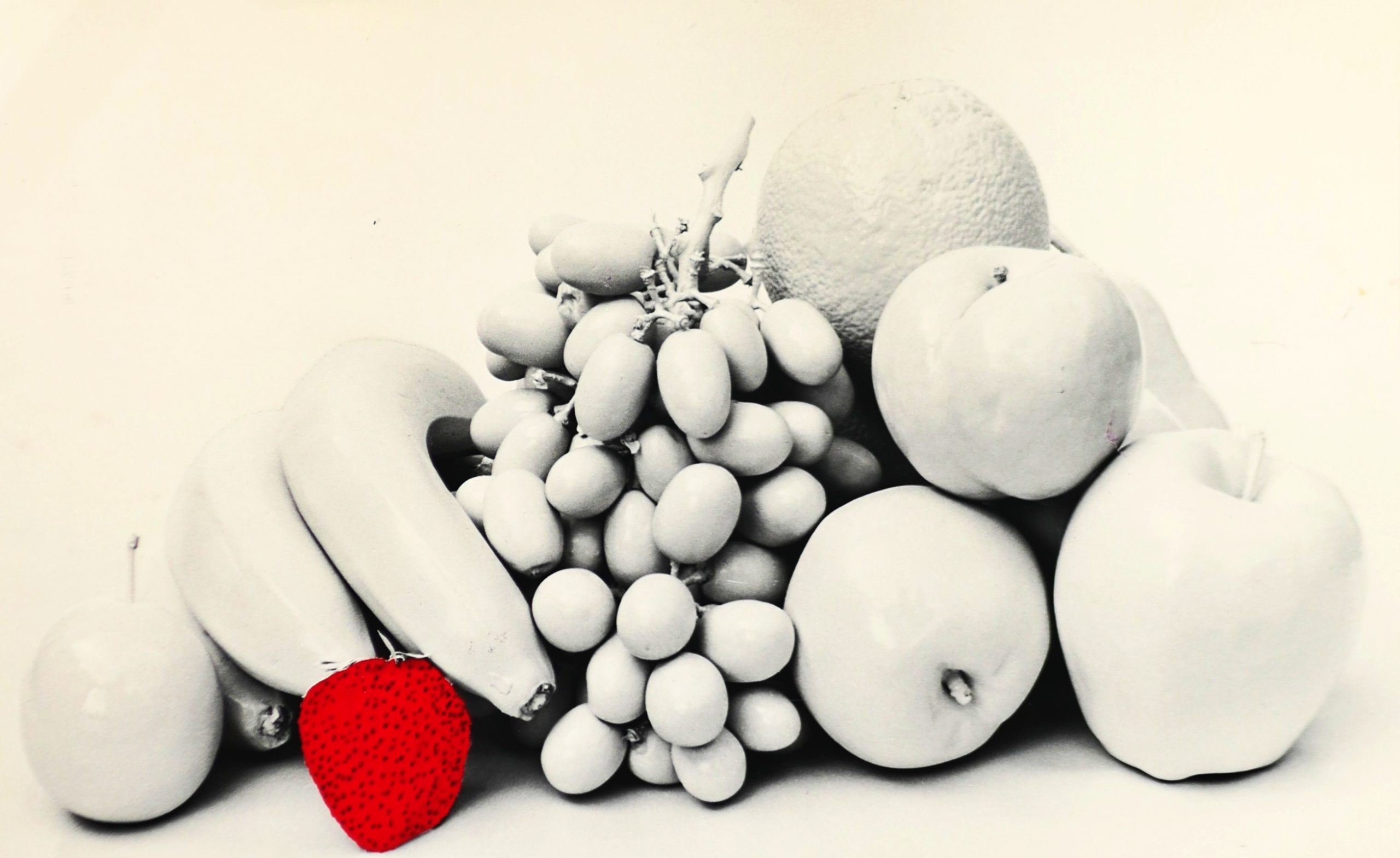 Black and white photo of well placed fruit, portrait of fruit with only a single colored red strawberry
